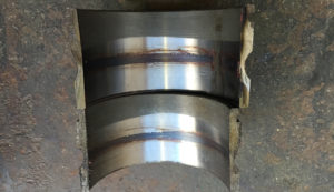 Metal cylinder cut in half showing signs of wear